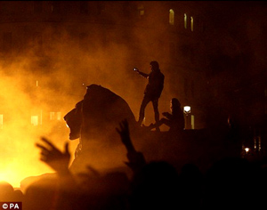 Nightfall: Riot police form lines in front of burning dustbins as they try to control protesters run rampage after the TUC's anti-cuts demonstrations (left) and protesters occupy Trafalgar Square last night.  